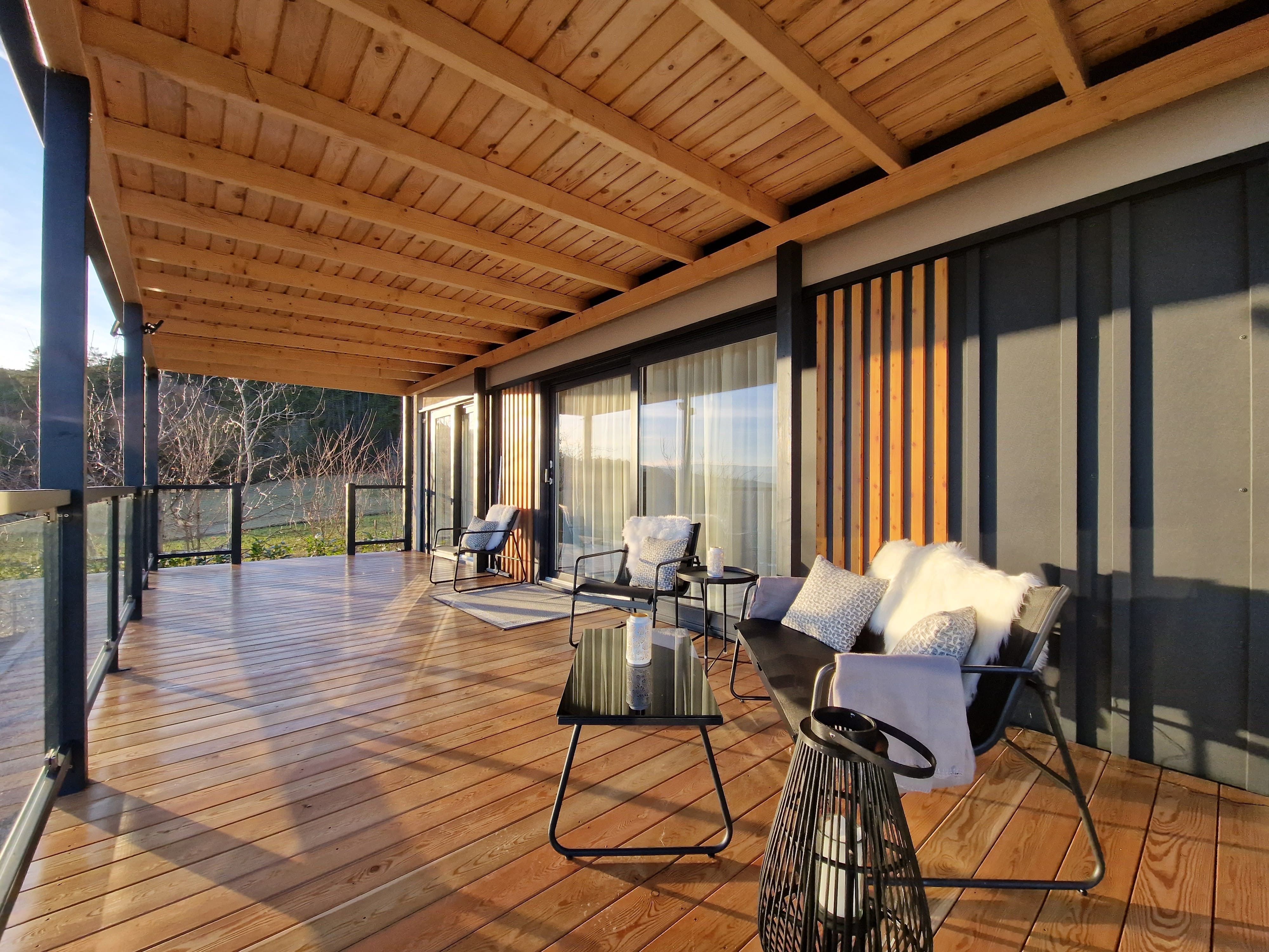 Modern terrace with wooden floor, glass railings and comfortable seating.