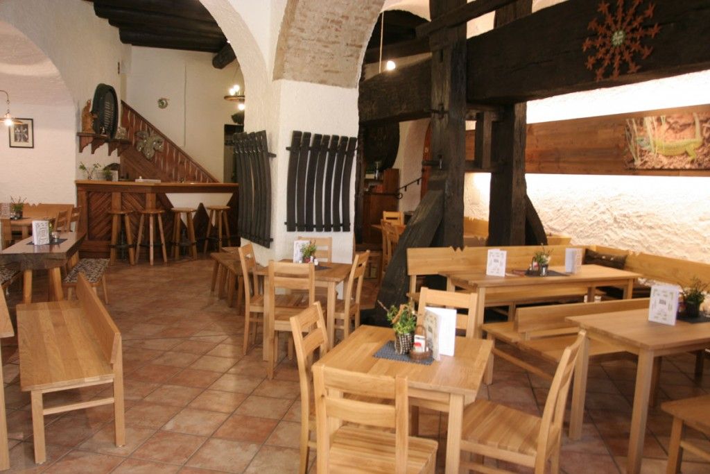 Interior view of a rustic wine tavern with wooden furniture and brick arches.