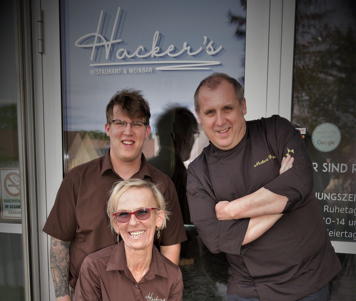 Three people in front of the entrance to Hacker's Restaurant & Wine Bar.