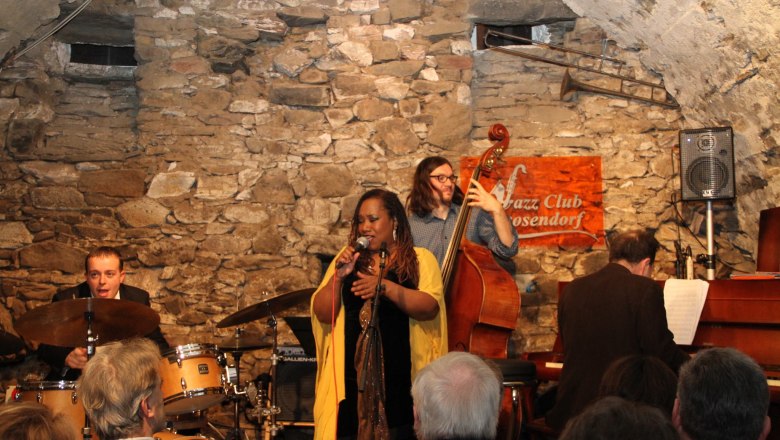 Jazz band plays in a rustic club with stone walls.