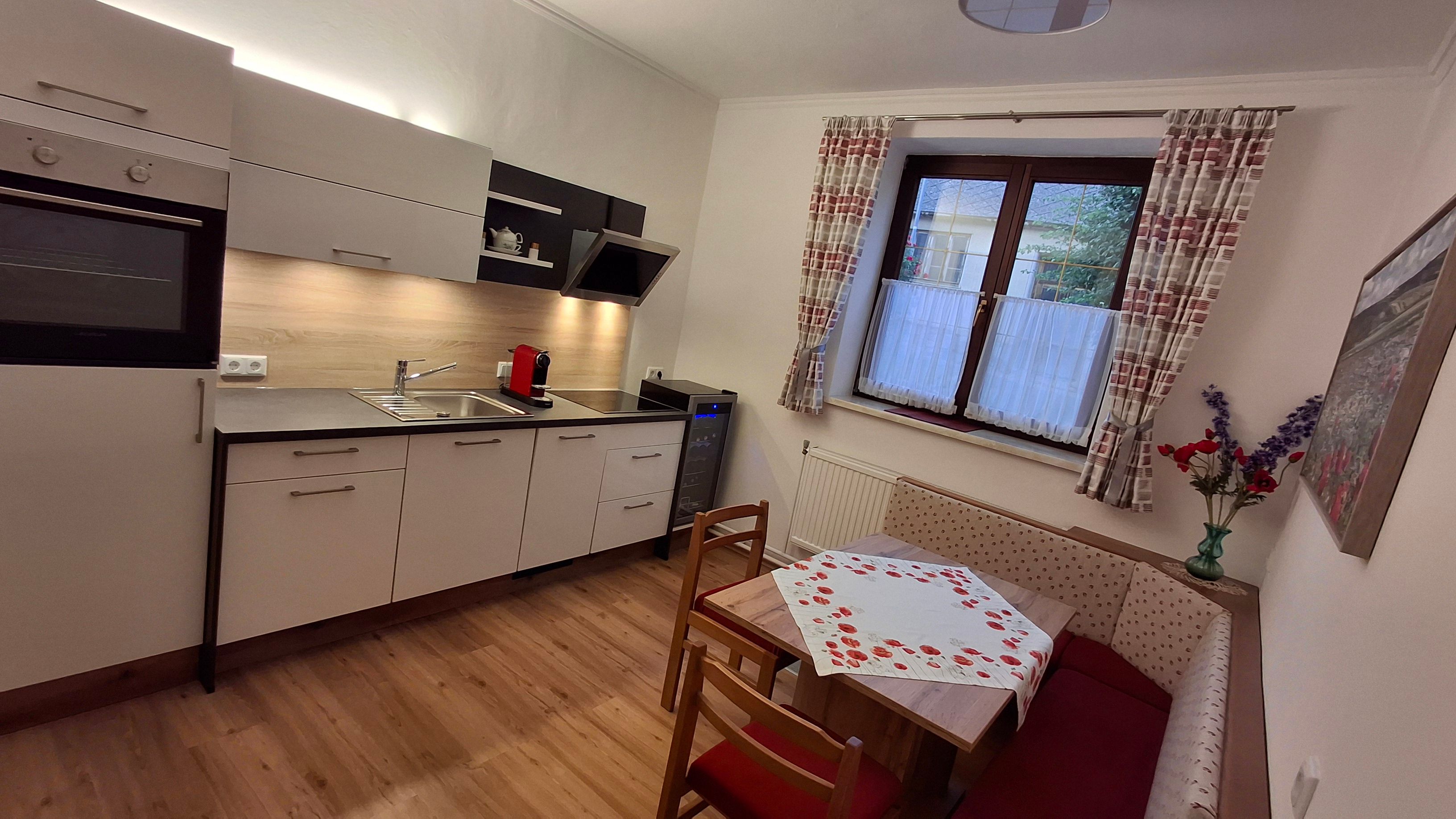 Modern kitchen with corner bench, table and window with curtains.
