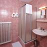 Bathroom with pink tiles, shower cubicle, washbasin and radiator.