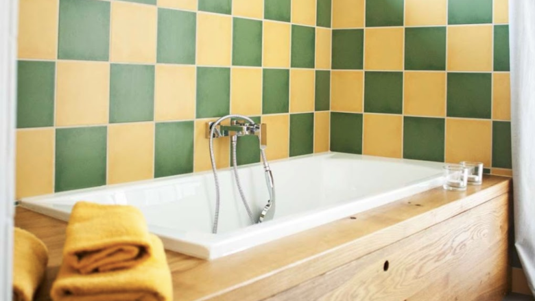 Bathroom with bathtub, yellow-green tiles and wood paneling.
