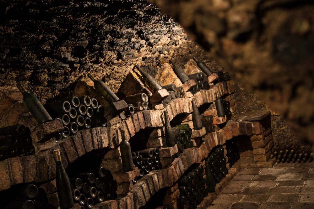 Wine cellar with old bottles on brick shelves.