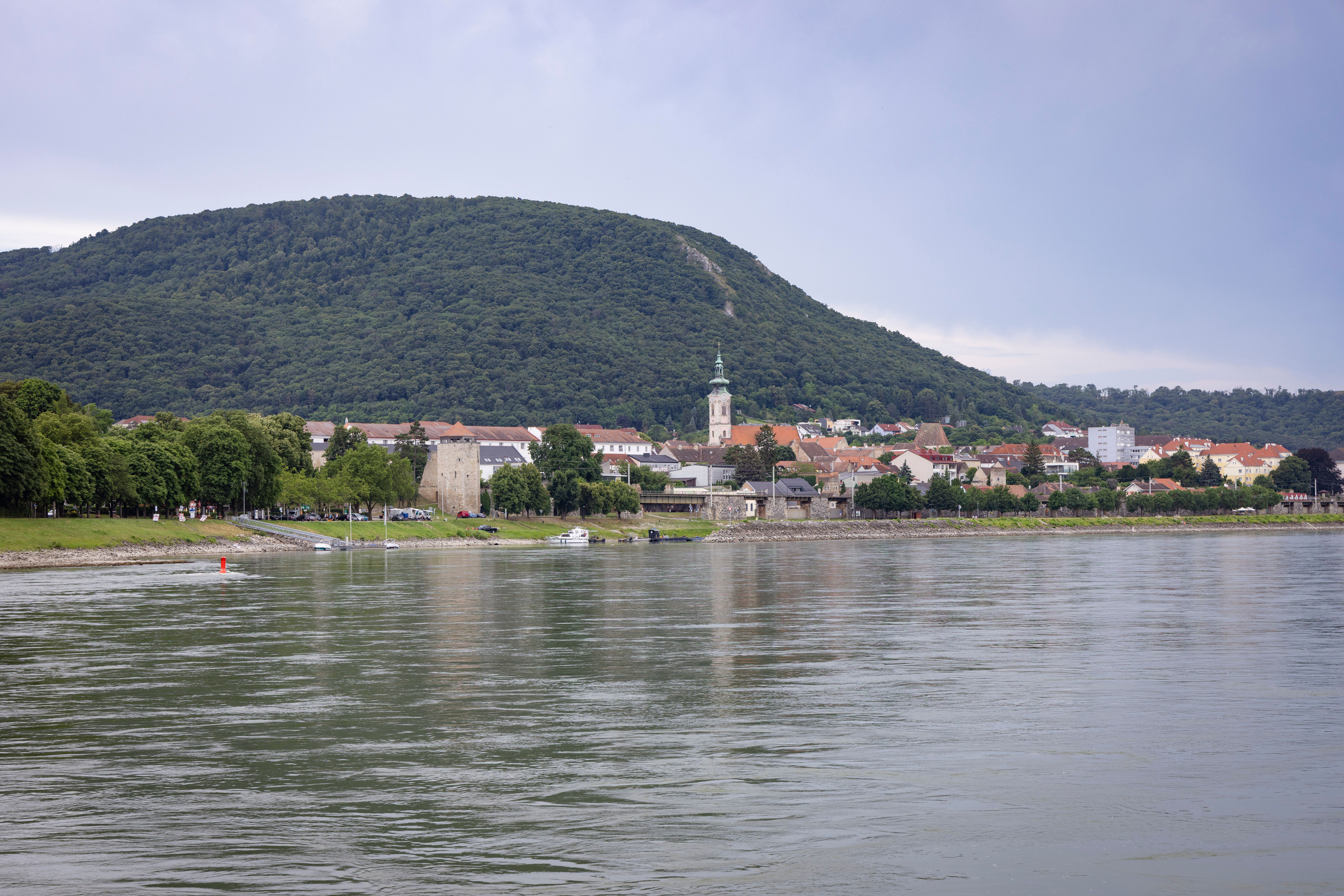 View of Hainburg/Danube on the river bank with a hill in the background.