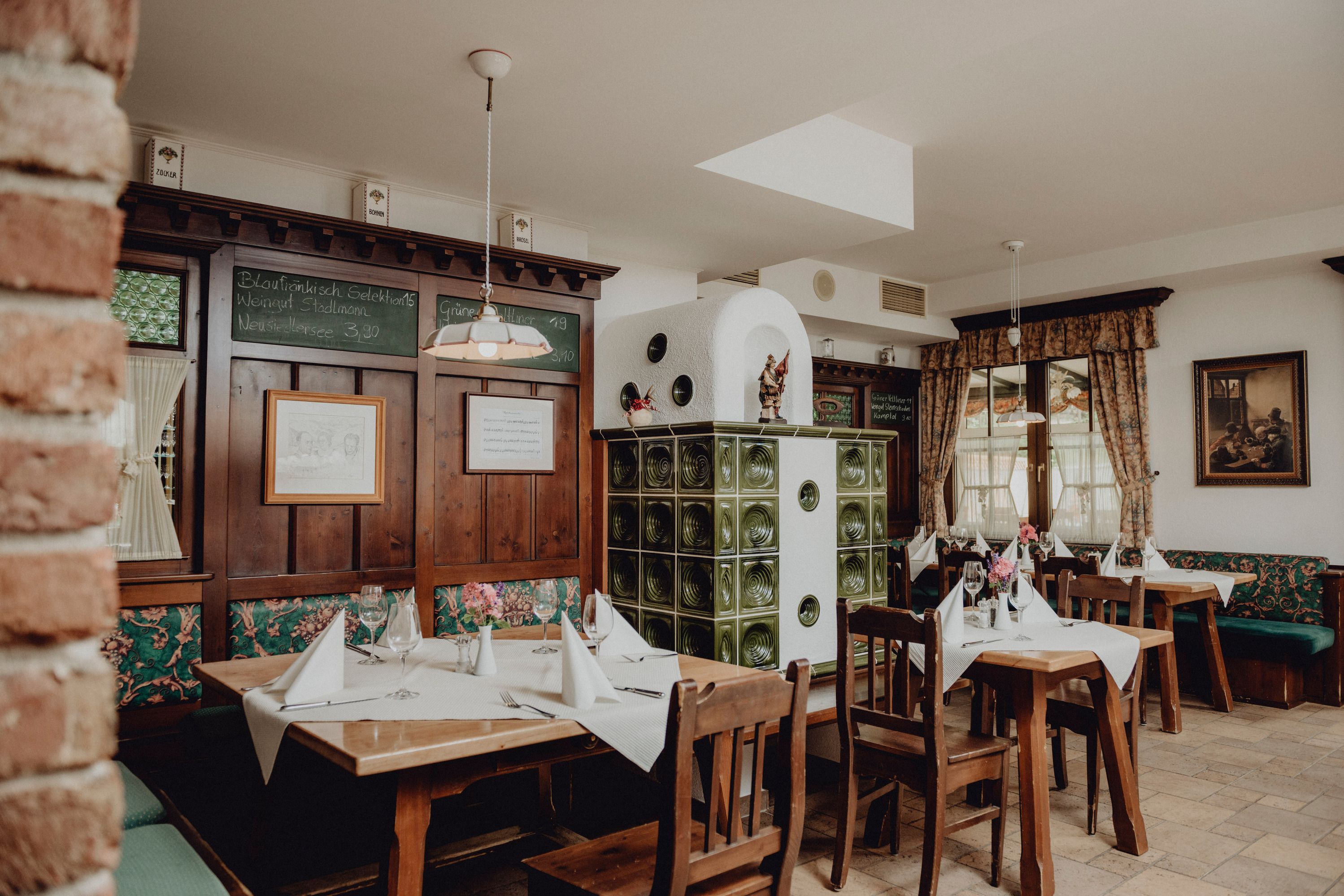 Cozy restaurant with wooden furniture, tiled stove and decorated tables.
