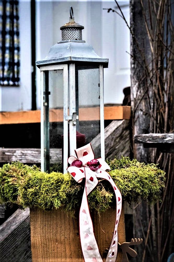 Lantern decorated with moss and ribbon.