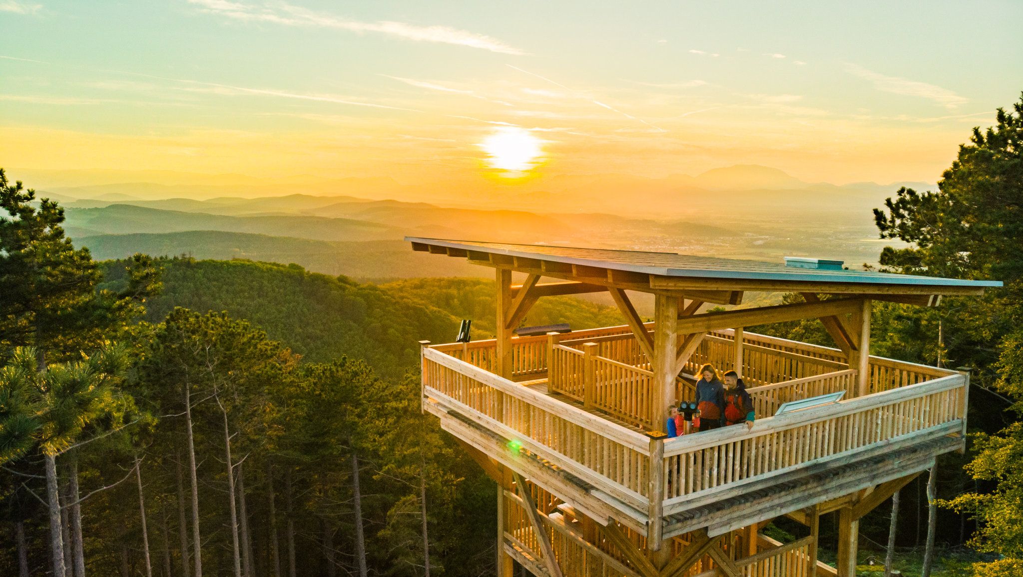 Observation tower in Lanzenkirchen at sunset with a view of wooded hills.