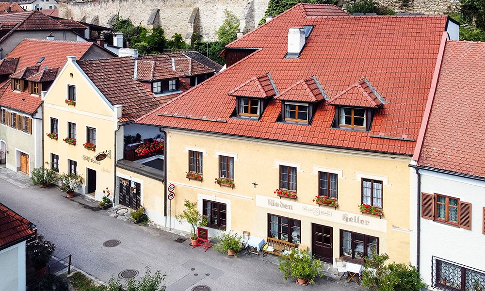 A traditional guest house with a yellow façade and red roofs in a quiet street.