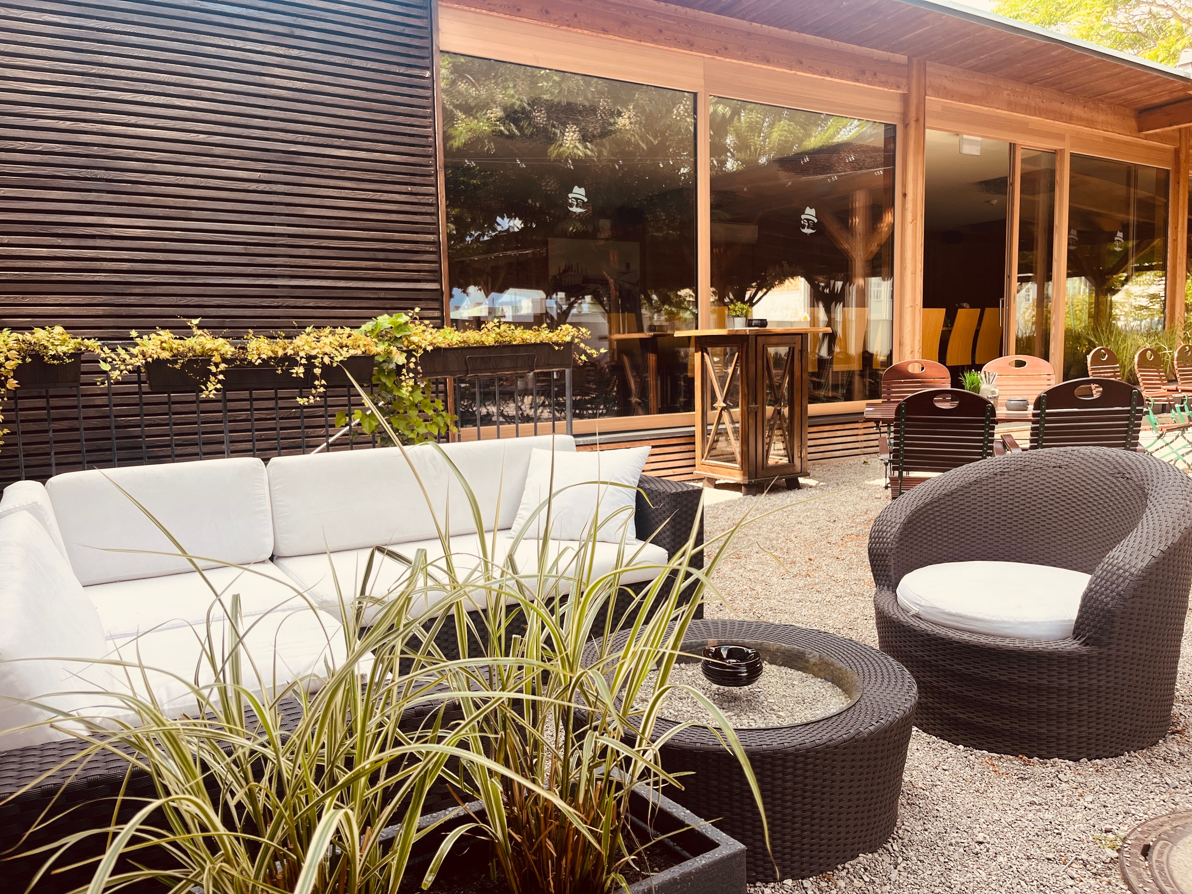 Cozy outdoor lounge with white sofas, round tables and plants.