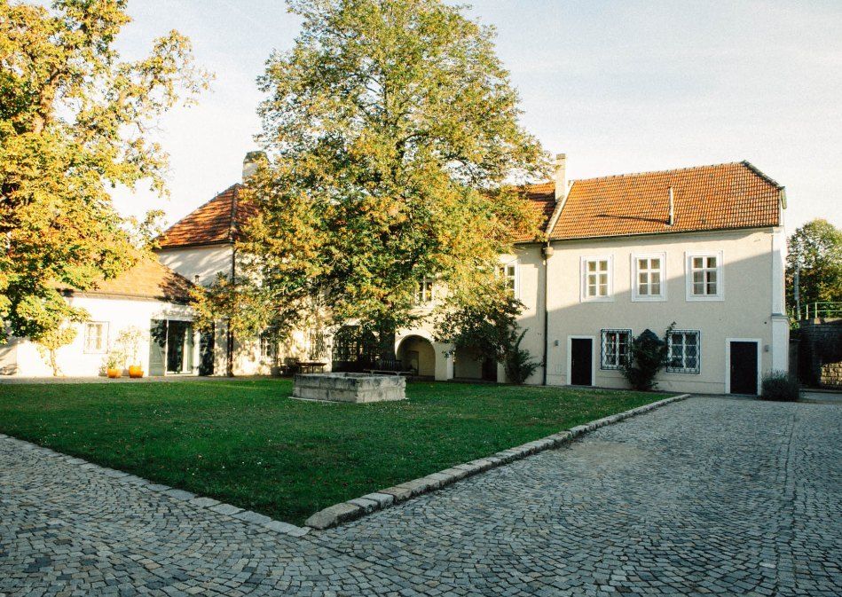 Inner courtyard of a historic building with paved path, lawn and trees.