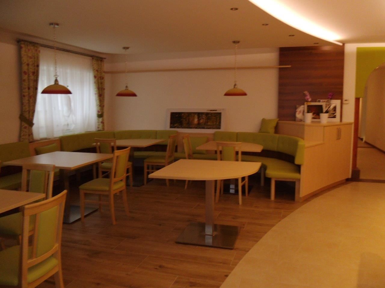 Interior view of a café with green benches and wooden tables.