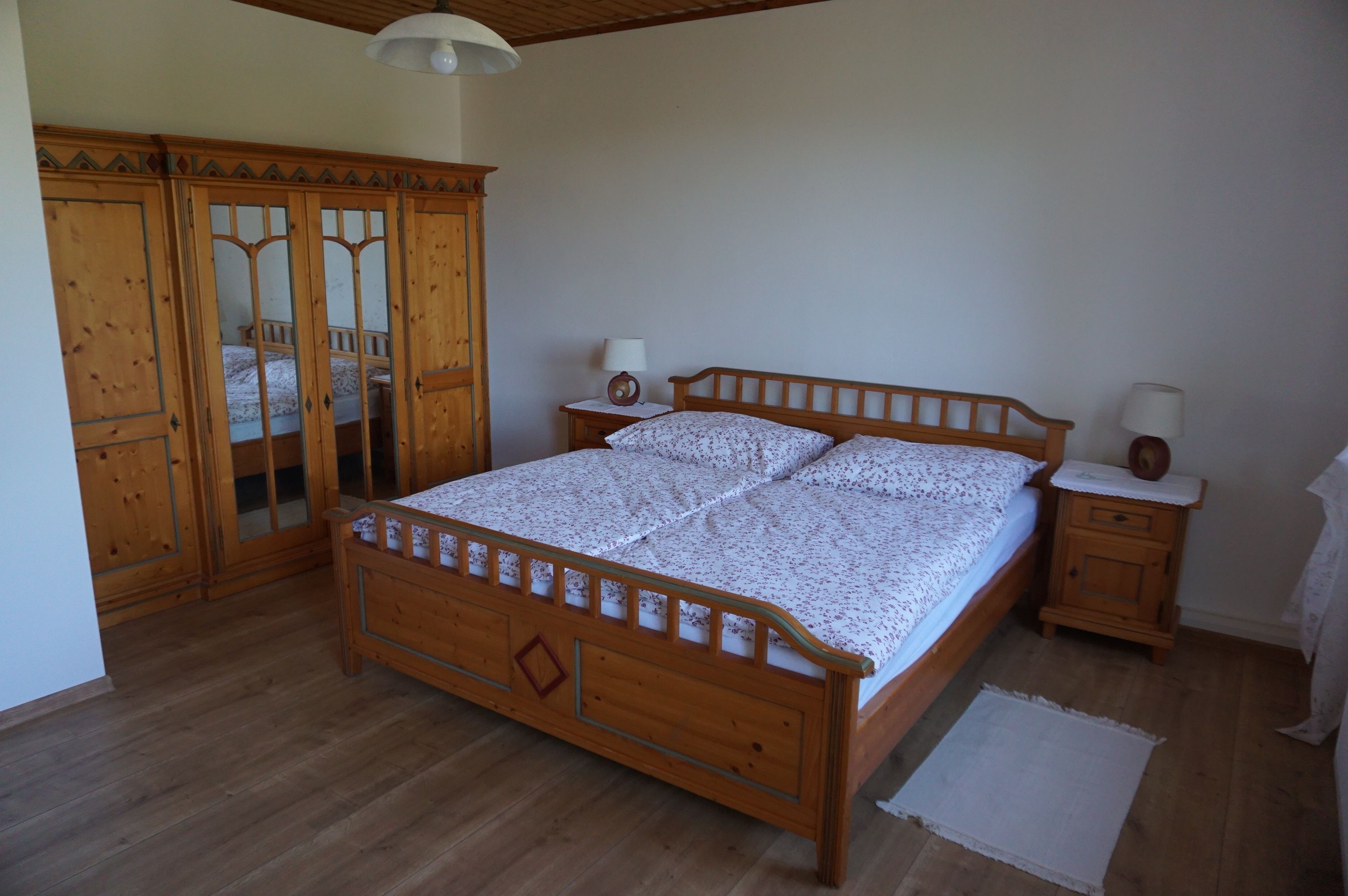 One bedroom with a wooden double bed, a closet with mirrors and two bedside tables with lamps.