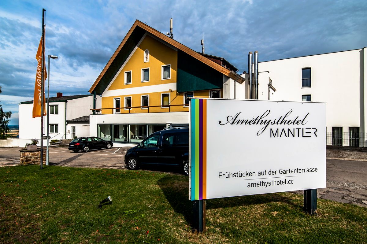 Exterior view of the Amethysthotel Mantler with parking lot and sign.