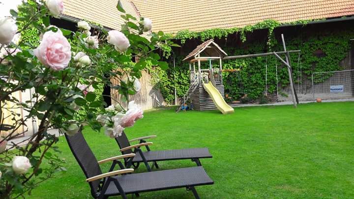 Inner courtyard with lawn, two sun loungers, rose bush and playground with slide.
