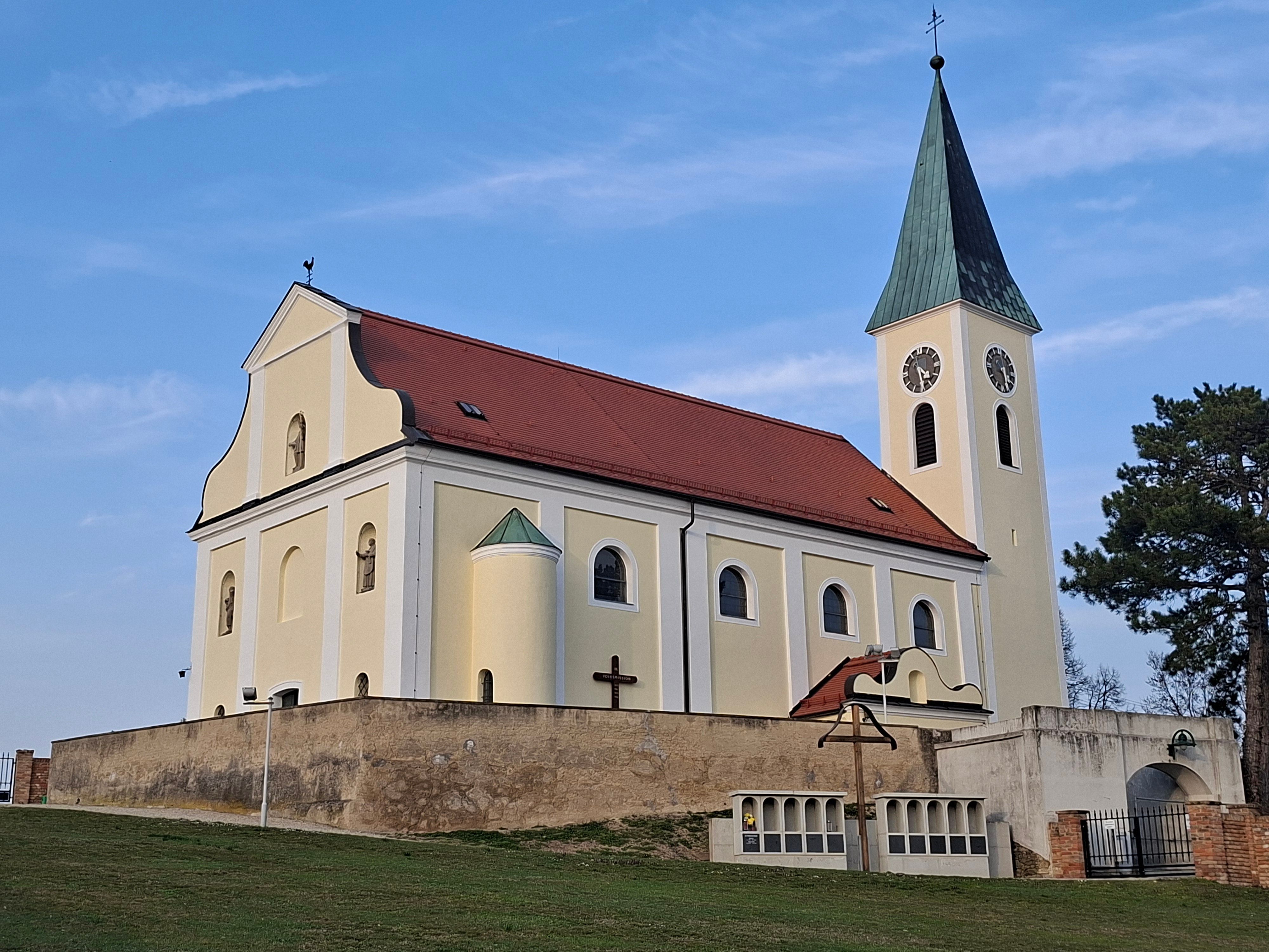 Church with yellow façade and red roof against a blue sky.