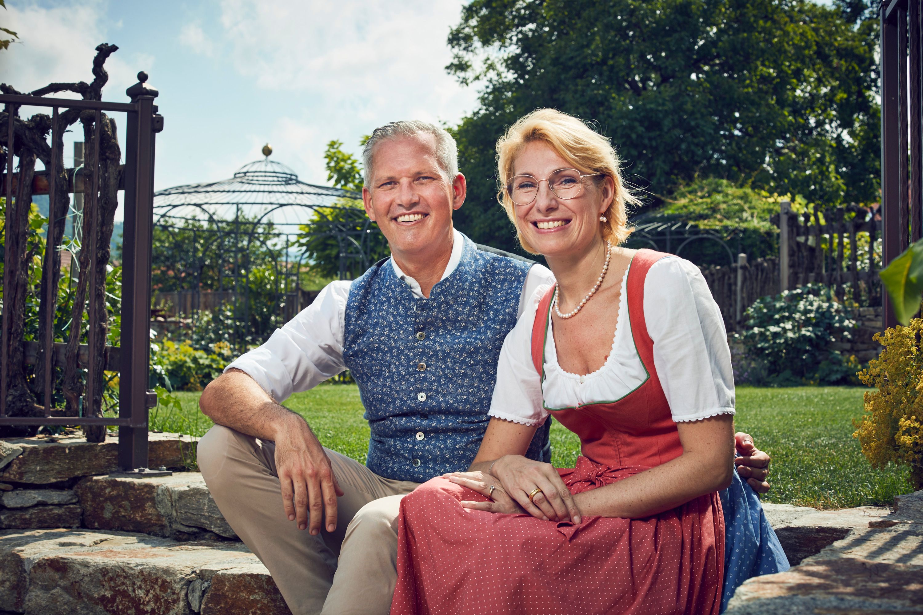 The Wildeis family in traditional costume sit smiling in the garden.