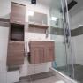 Modern bathroom with shower, washbasin and wooden cabinets.