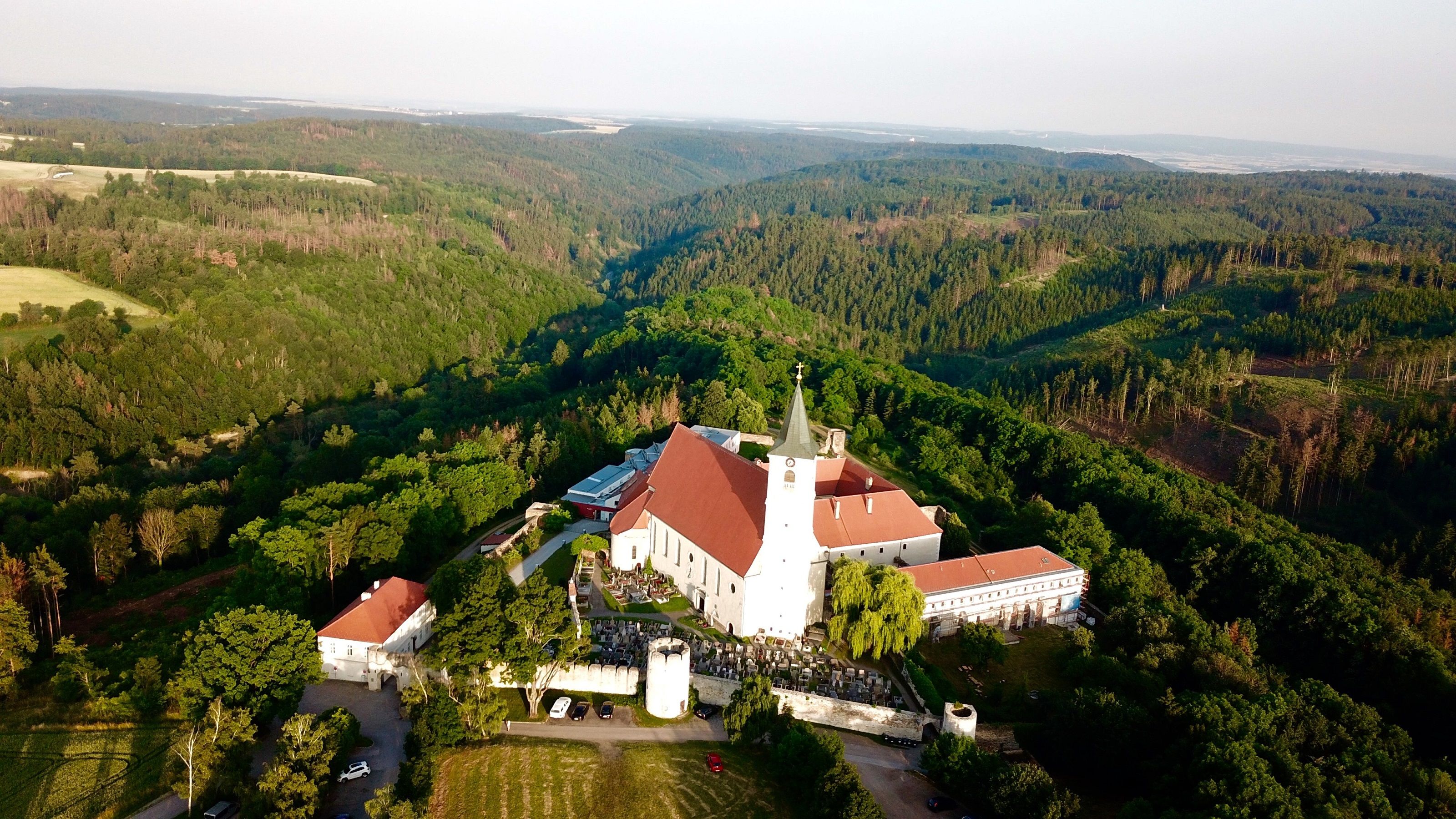 Aerial view of Pernegg Monastery surrounded by forest landscape.
