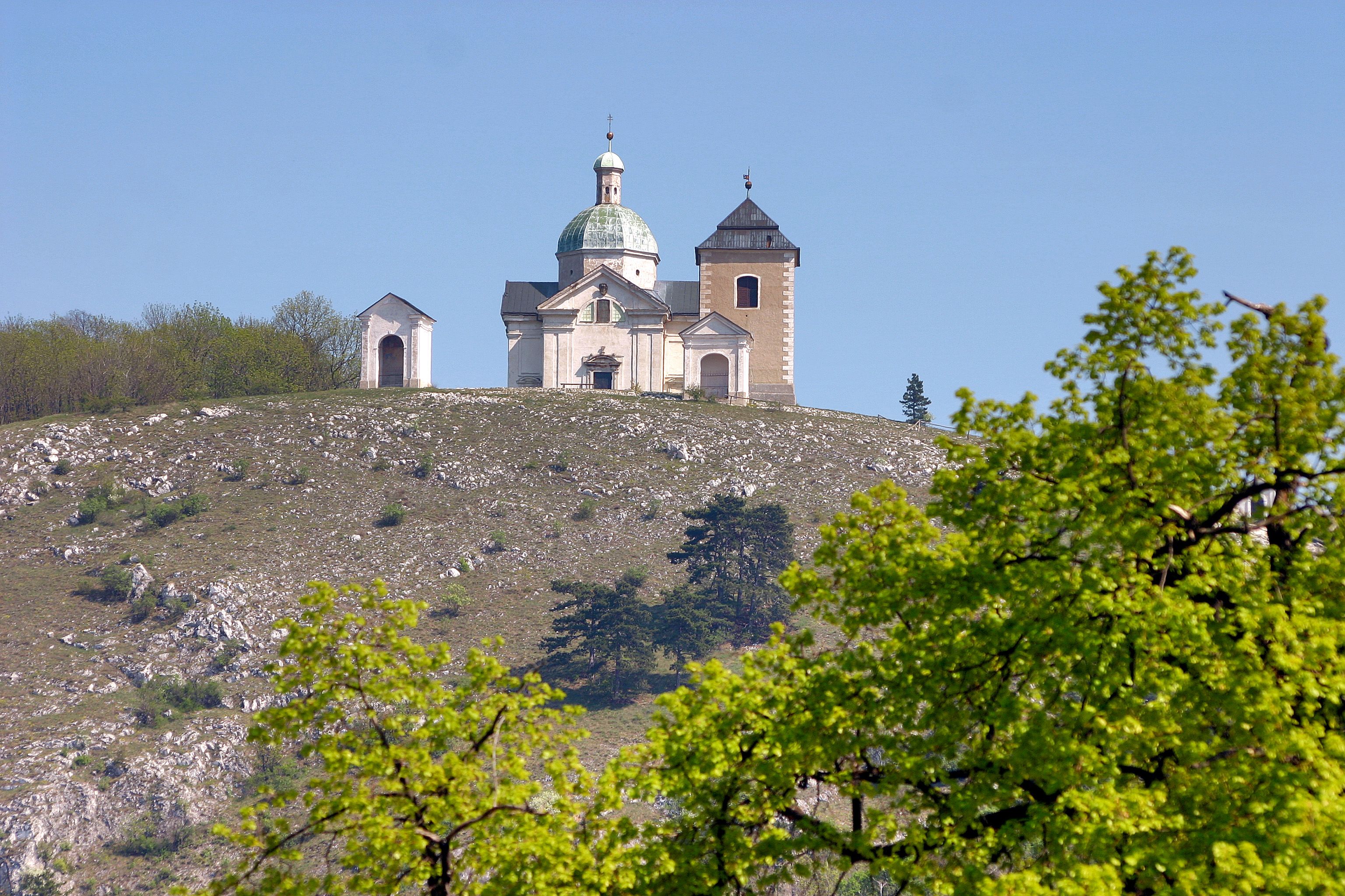 Church on a hill with trees in the foreground.