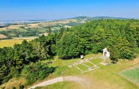 Landscape view from a lookout tower with forests, fields and a small chapel.