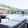 An outdoor pool with sun loungers and parasols set against a hilly landscape.
