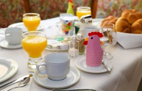 Breakfast table with orange juice, bread rolls and cups in a guesthouse.