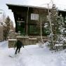 A skier passes a snow-covered building that serves as a restaurant.