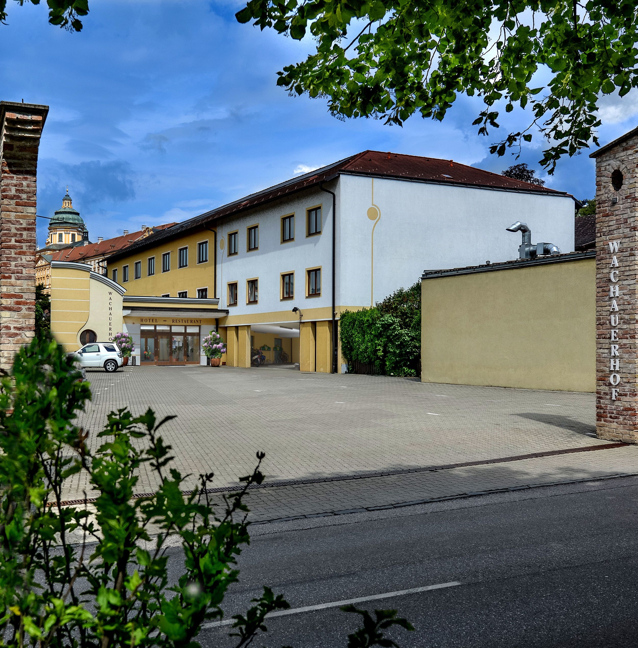 Exterior view of the Wachauerhof in Melk with parking lot and building facade.