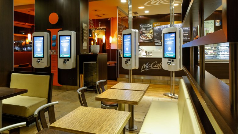 Interior view of a McDonald's restaurant with ordering terminals and seating areas.