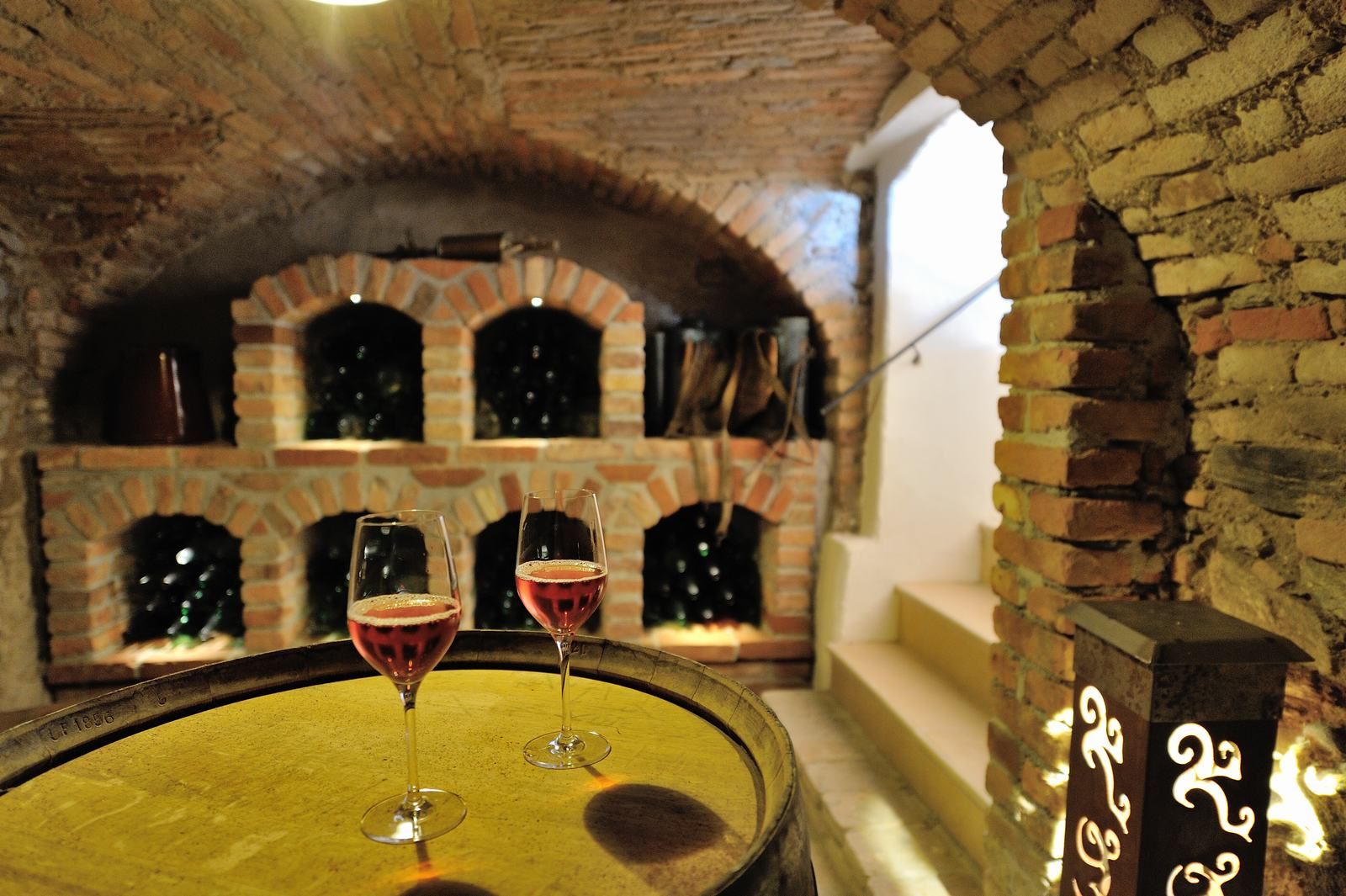 Wine cellar with two glasses of rosé wine on a barrel.