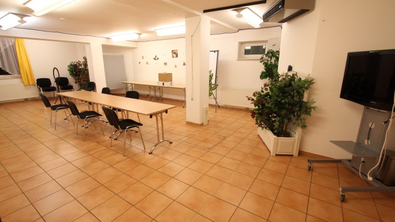 A bright seminar room with tables, chairs and plants.