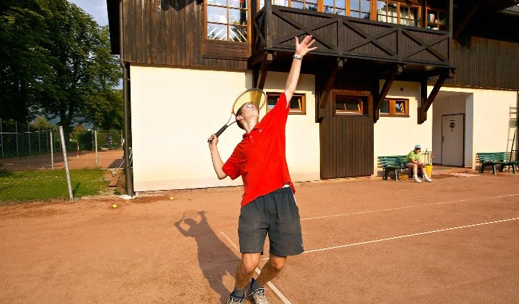 Person playing tennis in front of a building.