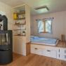 Interior view of a modular house with wood stove, shelf and bed.