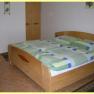 One bedroom with a double bed, wooden furniture and green bed linen.