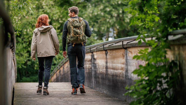 Two hikers on a wooden bridge in the forest