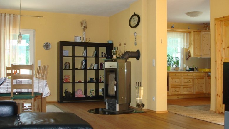 Kitchen-living room with wooden furniture, dining table, shelving, fireplace and open kitchen.