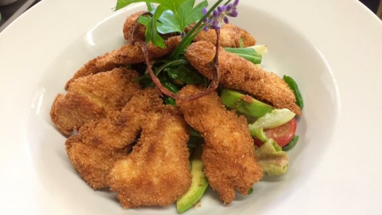A plate with salad and baked goods, garnished with herbs.