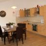 Dining area with wooden table and chairs, next to a modern kitchen with wooden cupboards.