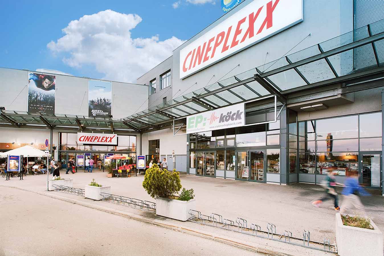 Entrance to the Cineplexx cinema in Wiener Neustadt with glass roof and advertising posters.