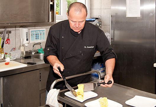 A chef cuts an omelette in a professional kitchen.