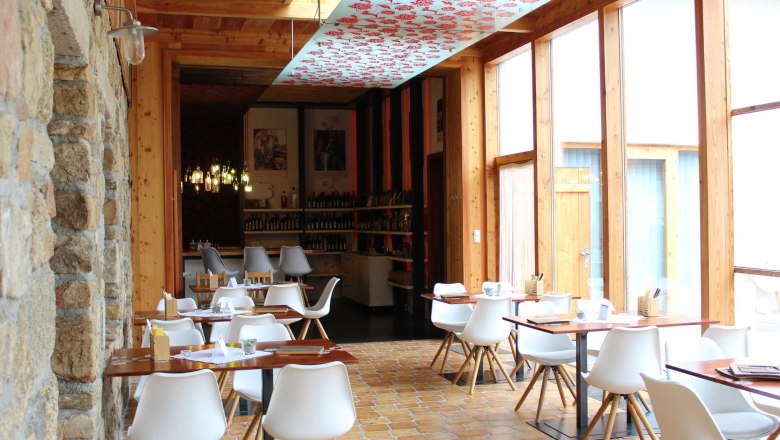 Interior view of a modern restaurant with white chairs and wooden tables.