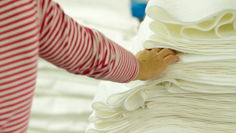 A hand touches a pile of white towels.