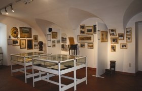 Interior view of a museum room with display cases and historical photos on the walls.