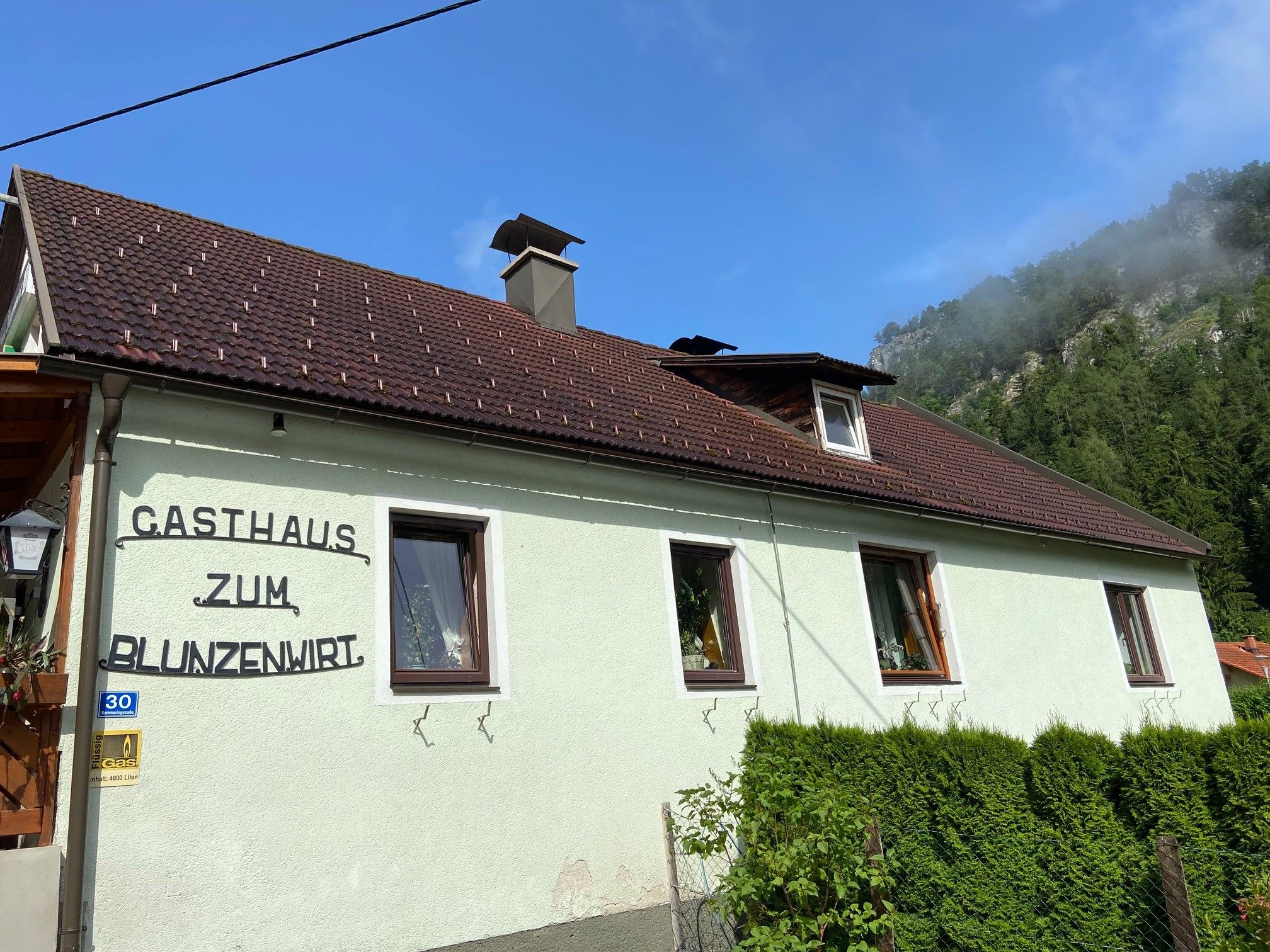 Exterior view of the Zum Blunzenwirt inn with green paint and brown roof.