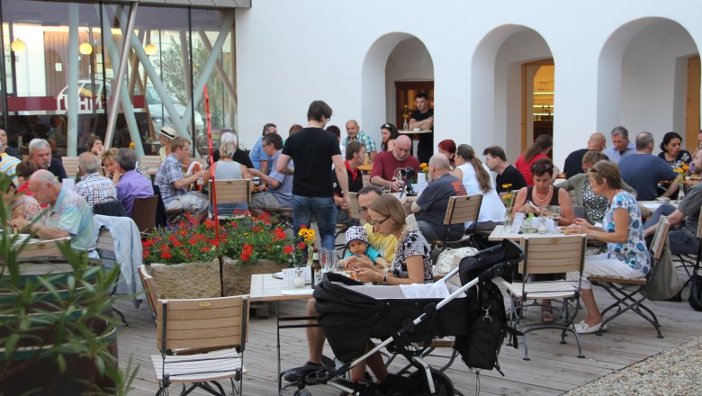 People sit at tables in an inner courtyard and eat.