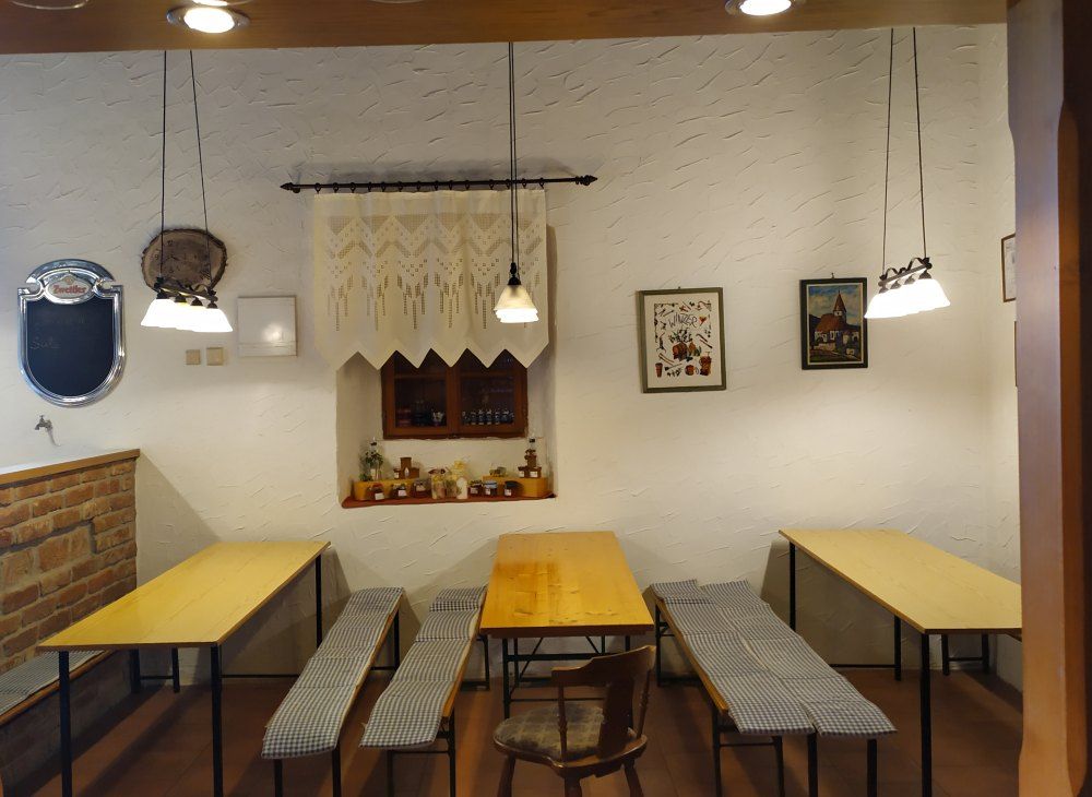Cozy parlor with wooden tables and benches, decorated with pictures and lamps.