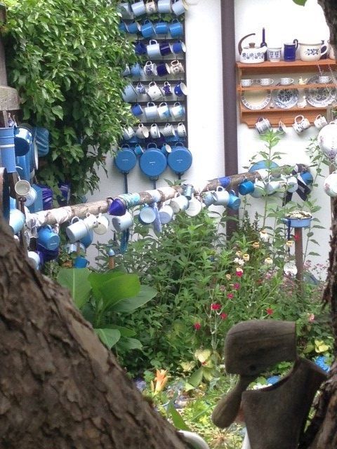 A garden with lots of colorful cups hanging on walls and poles.