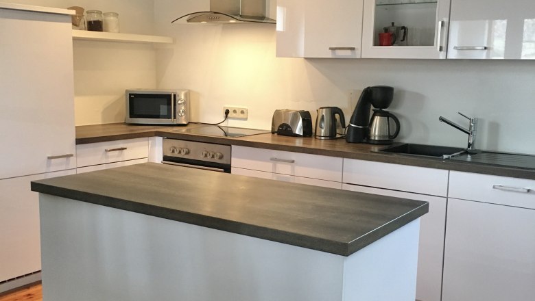 Modern kitchen with island, white cupboards and appliances.