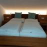 A double bed in a room with a sloping ceiling, two pillows and bedside tables.